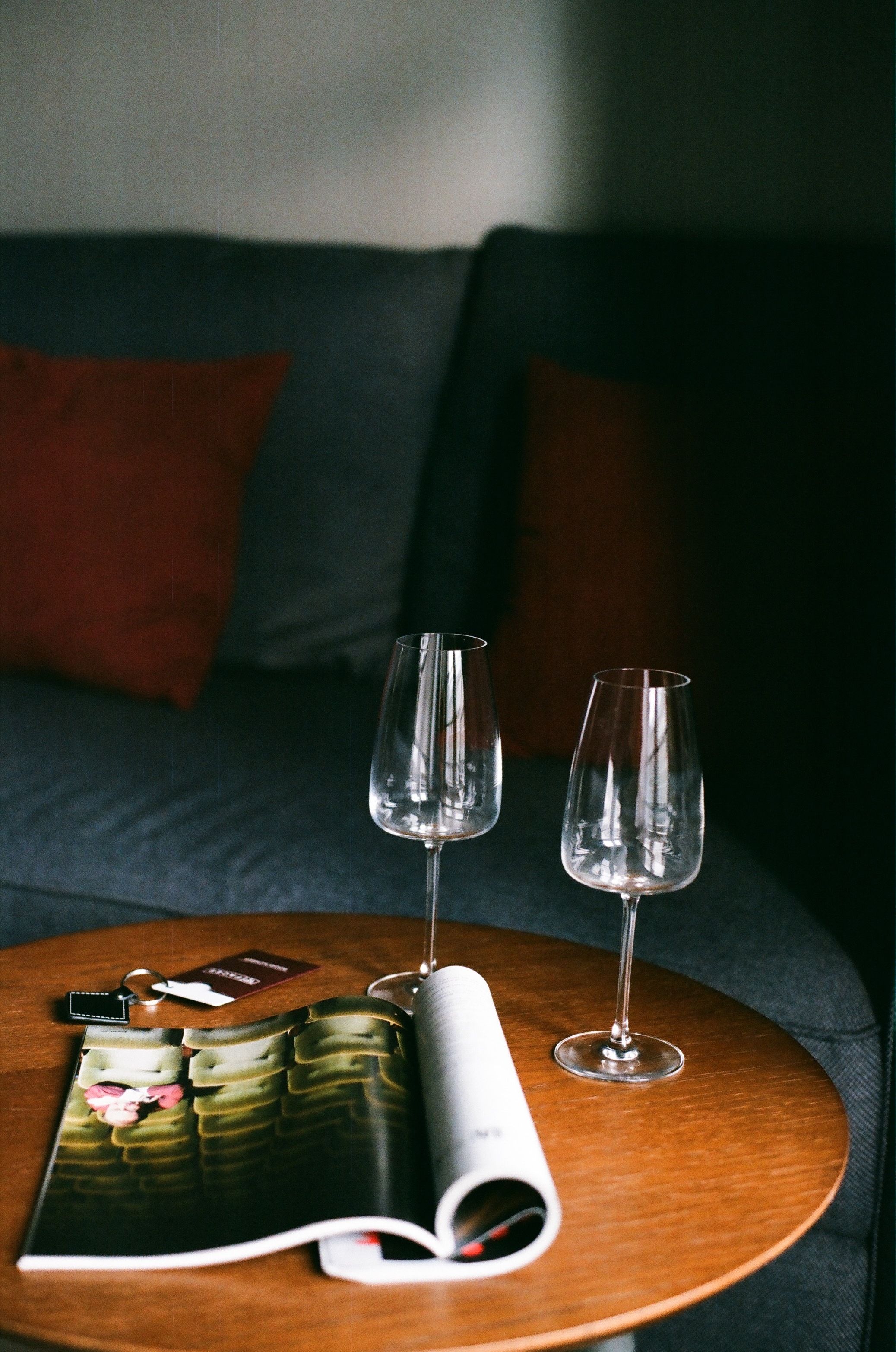 Cozy living room setup with wine glasses on a round wooden table.