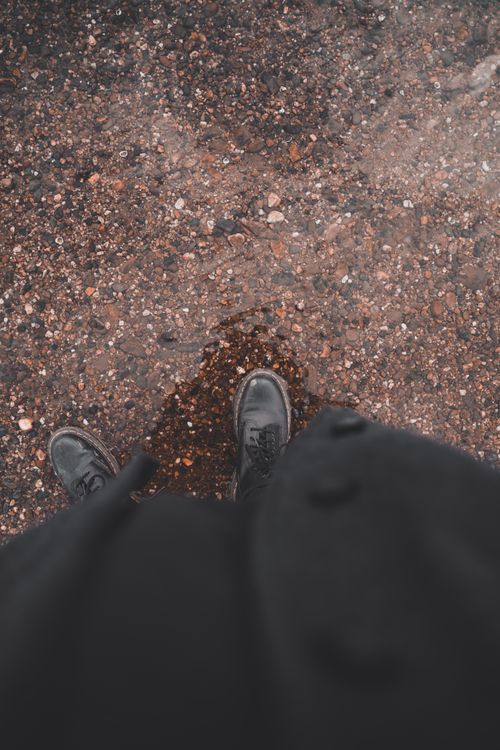 Free A view from above as black shoes stand on a wet, pebbled surface in Dresden, Germany. Stock Photo