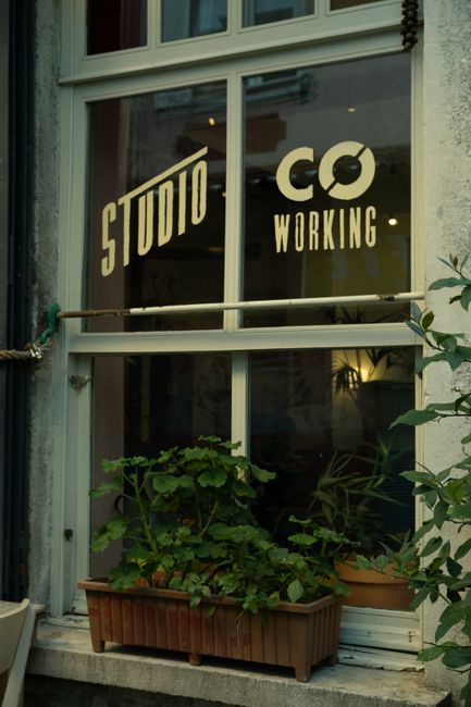 Photo by Gül Işık Close-up of a vintage coworking space window with plants and signage, perfect for creative workspaces.