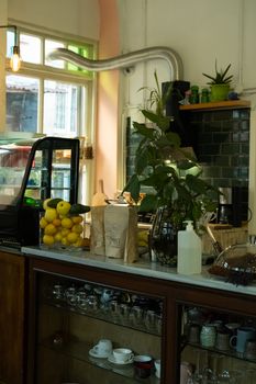 Charming cafe interior with a counter, lemons, and plants creating a warm atmosphere.