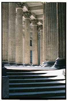 View of grand neoclassical columns casting shadows on stone steps in Saint Petersburg.
