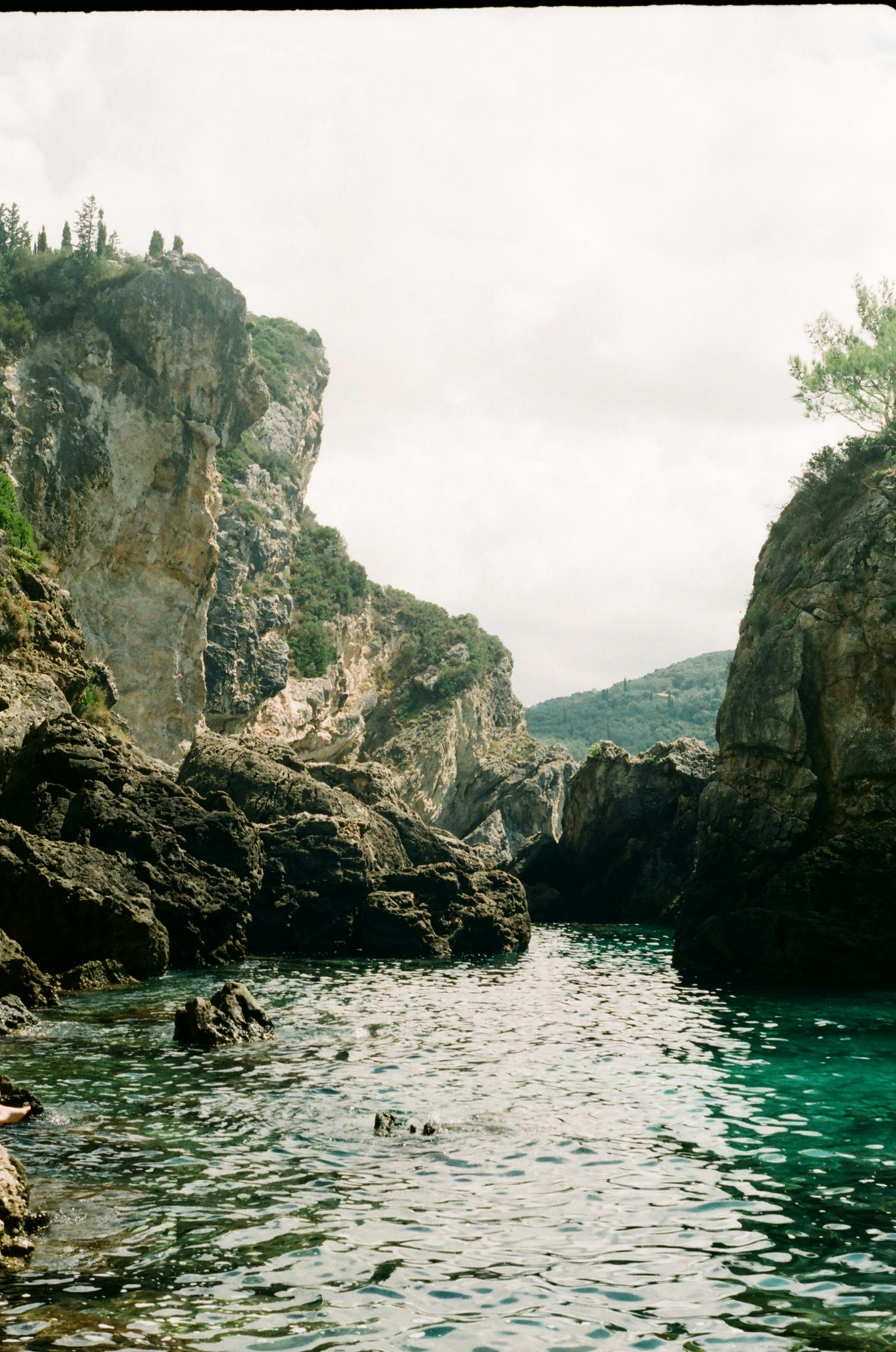 Tranquil rocky cove with clear emerald waters beneath a bright sky, ideal for nature enthusiasts.