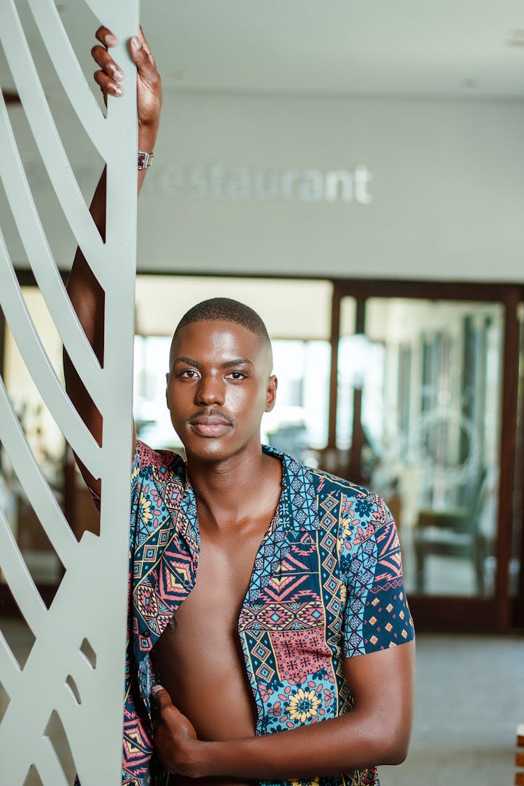 Man In Unbuttoned Colorful Shirt Posing Against Pole