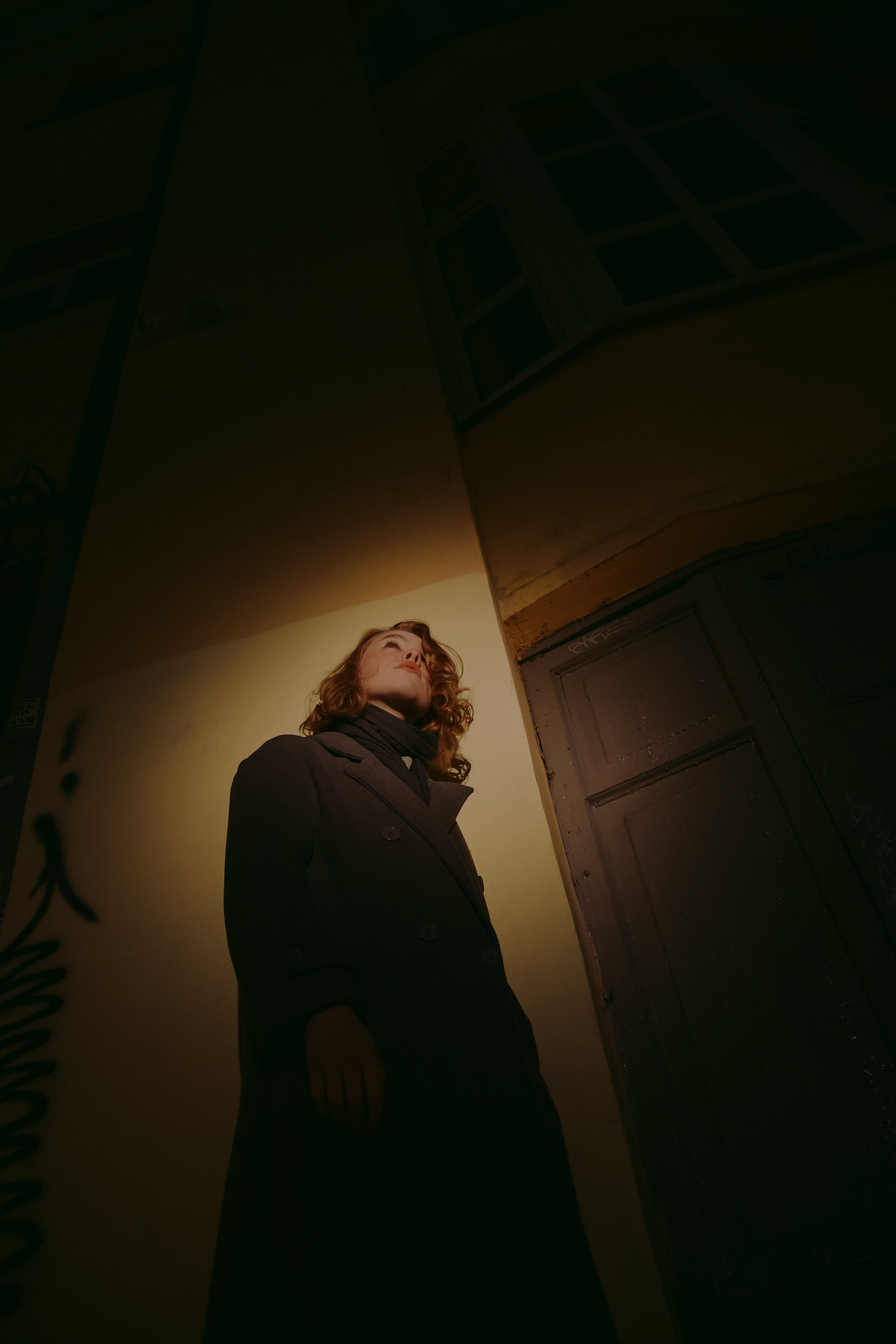 Low-Angle Shot of Woman in Black Coat Standing Near a Wall · Free Stock ...