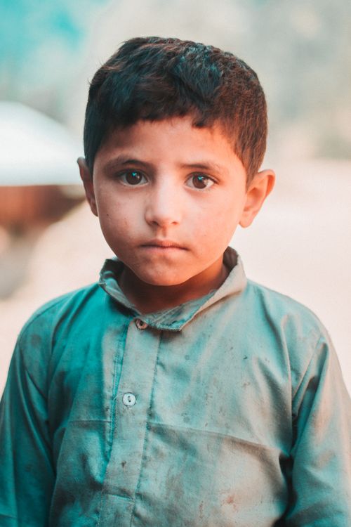 Free A young boy wearing traditional attire gazes directly at the camera outdoors. Stock Photo