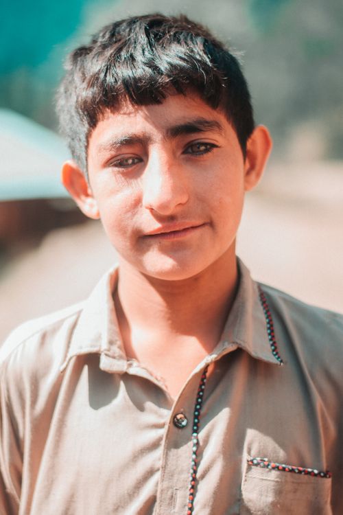 Free Close-up portrait of a young boy outdoors in natural light, displaying a warm, candid expression. Stock Photo