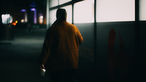 Back View Shot of a Woman Wearing Brown Jacket while Walking on the Street 