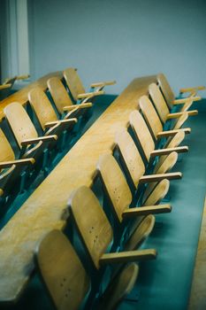 A row of empty wooden folding chairs in a well-lit classroom setting.