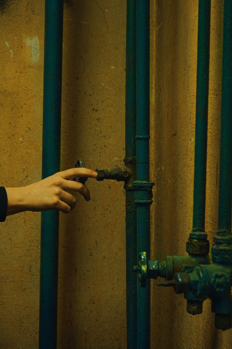 Person gripping a metal pipe against a concrete wall