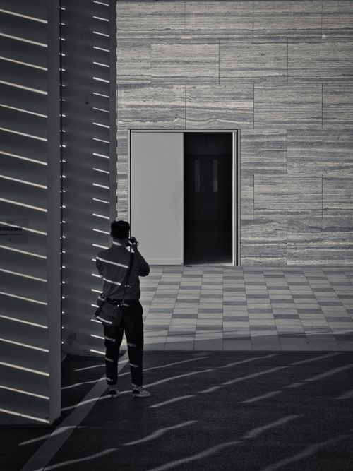 Free A photographer takes a picture of modern architecture in a monochrome setting. Stock Photo