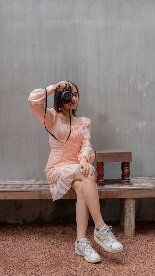 Woman in Pink Dress Sitting on Brown Wooden Bench