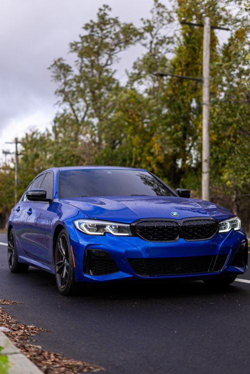 Free A stylish blue BMW parked on a street in Philadelphia, showcasing luxury and modern design. Stock Photo