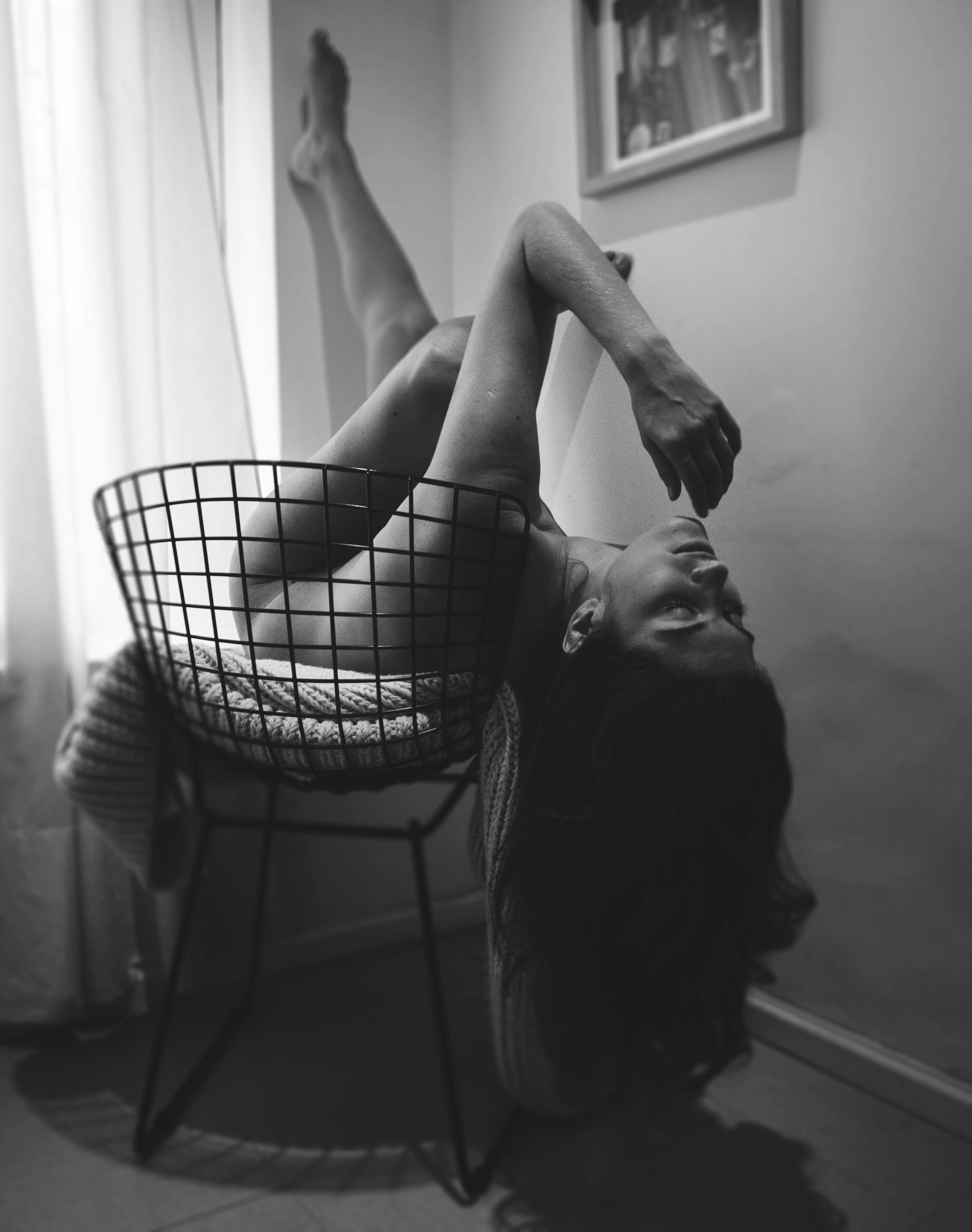 monochrome photography of a naked woman lying on black chair