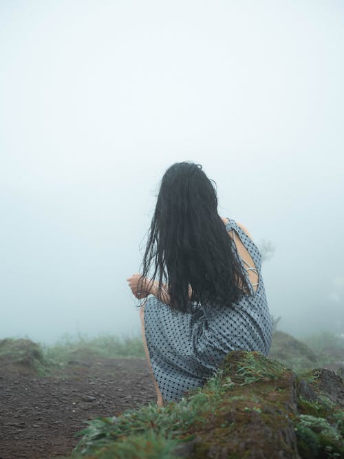 Brunette Woman in Dress Sitting on Rock