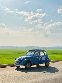 A classic vintage Citroen driving along a rural road on a sunny day in Antananarivo.