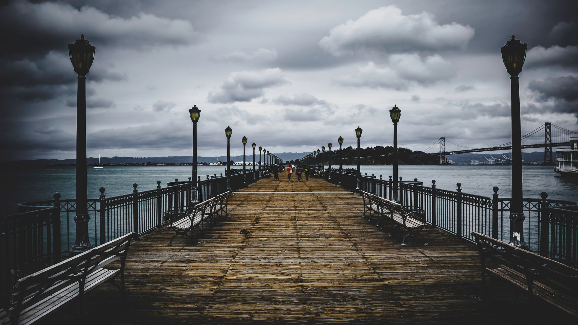 Dramatic scene of a pier leading to the Bay Bridge with moody clouds overhead, San Francisco.