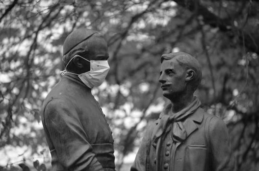 Monochrome photo of statues, one wearing a face mask, in Rhede, Germany.