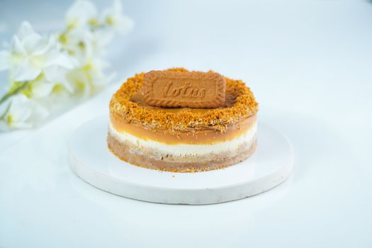 Indulge in a caramel Biscoff cheesecake on a white plate with flowers.