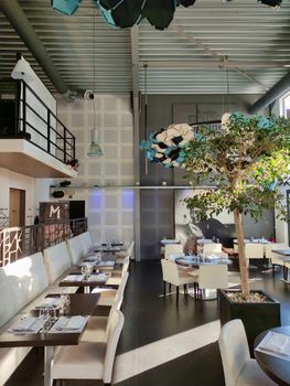 Stylish modern restaurant interior featuring elegant tables and a decorative tree.