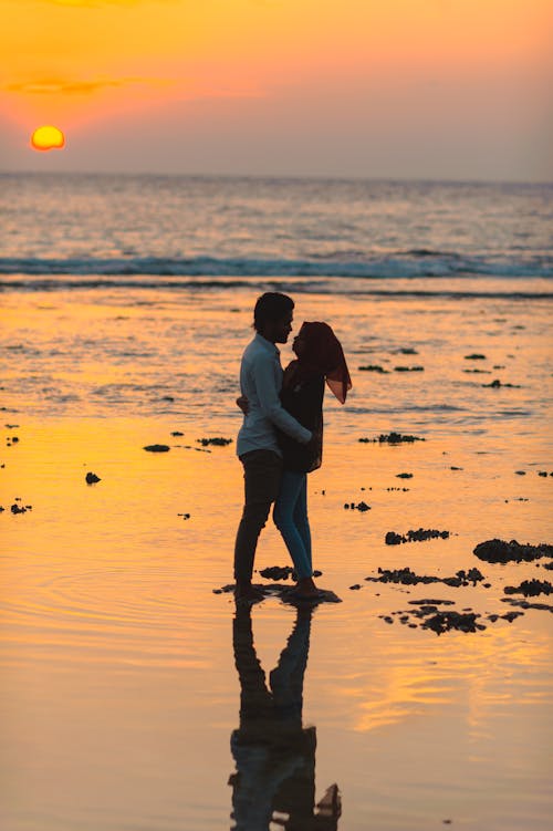 Man and Woman Hugging by the Seashore during Sunset