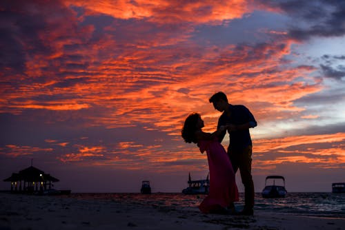 Gratis Pria Dan Wanita Di Pantai Saat Matahari Terbenam Foto Stok