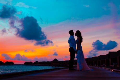 Homem E Mulher Vestindo Trajes De Casamento Em Pé Na Doca Do Mar Durante A Hora Dourada