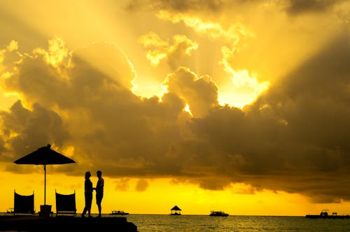 Free Silhouette Photo of Man and Woman Beside Body of Water during Sunset Stock Photo