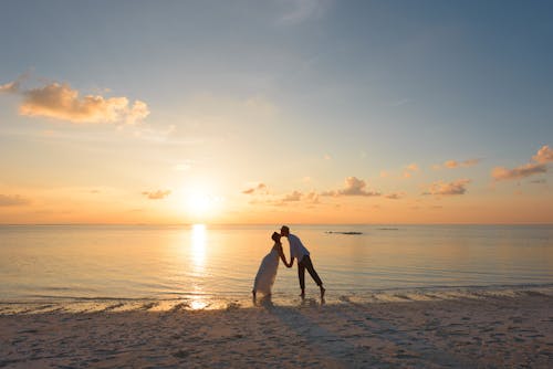 Free Man and Woman Standing on Shore Kissing Stock Photo