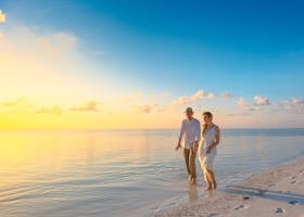 Couple Walking on Seashore Wearing White Tops during Sunset