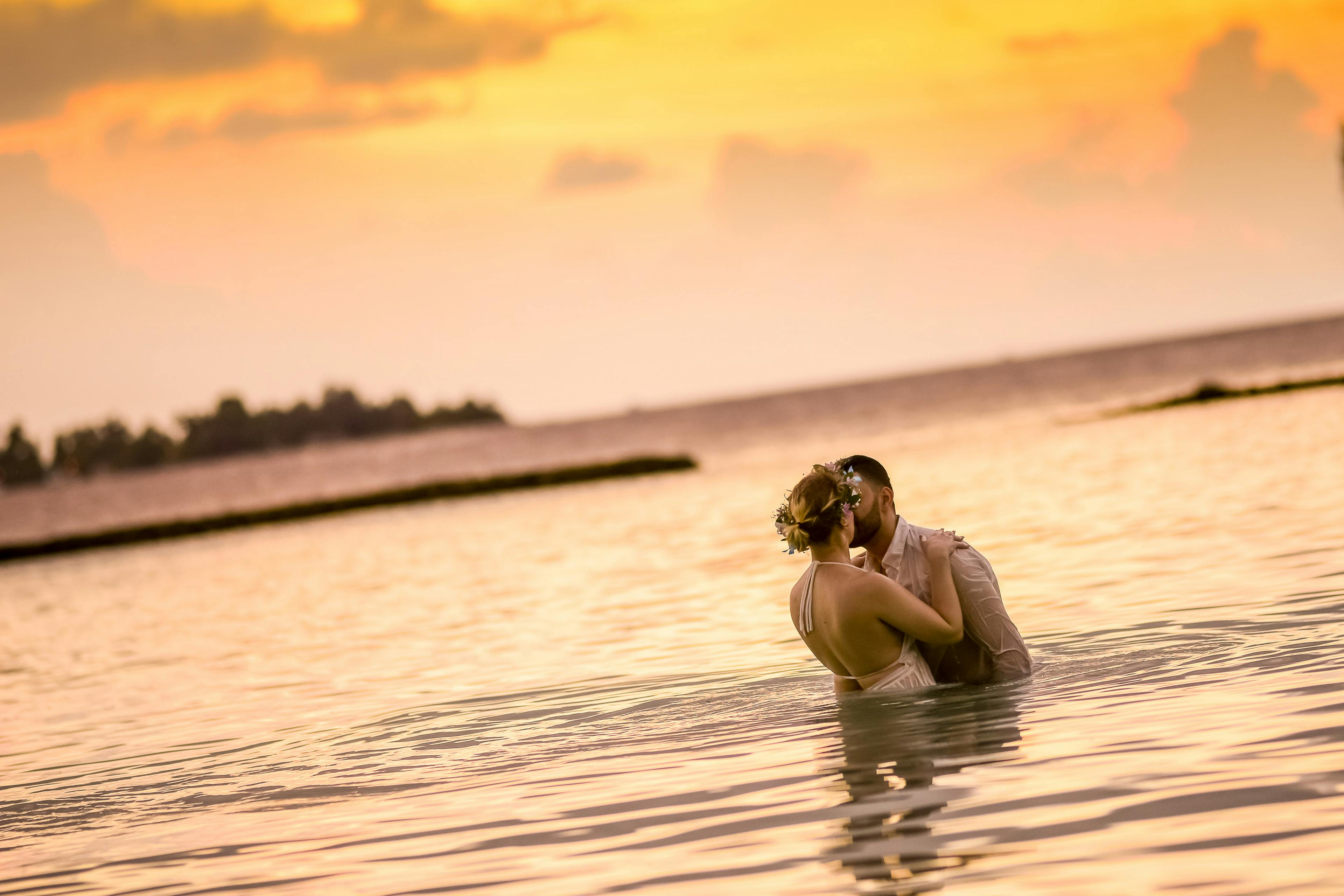 woman and man kissing in body of water