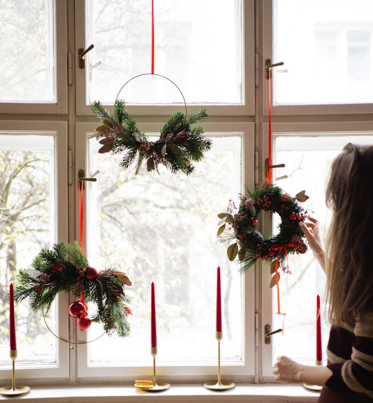 Woman Hanging Christmas Decorations By Windows