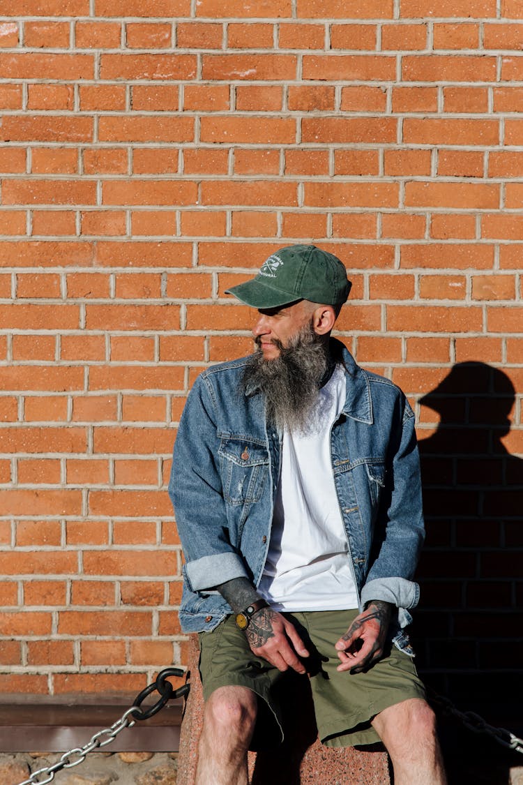 Adult Bearded Man In Cap Posing On Red Brick Wall Background