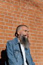 Skinny Tattooed Bearded Man Posing on Brick-Wall Background