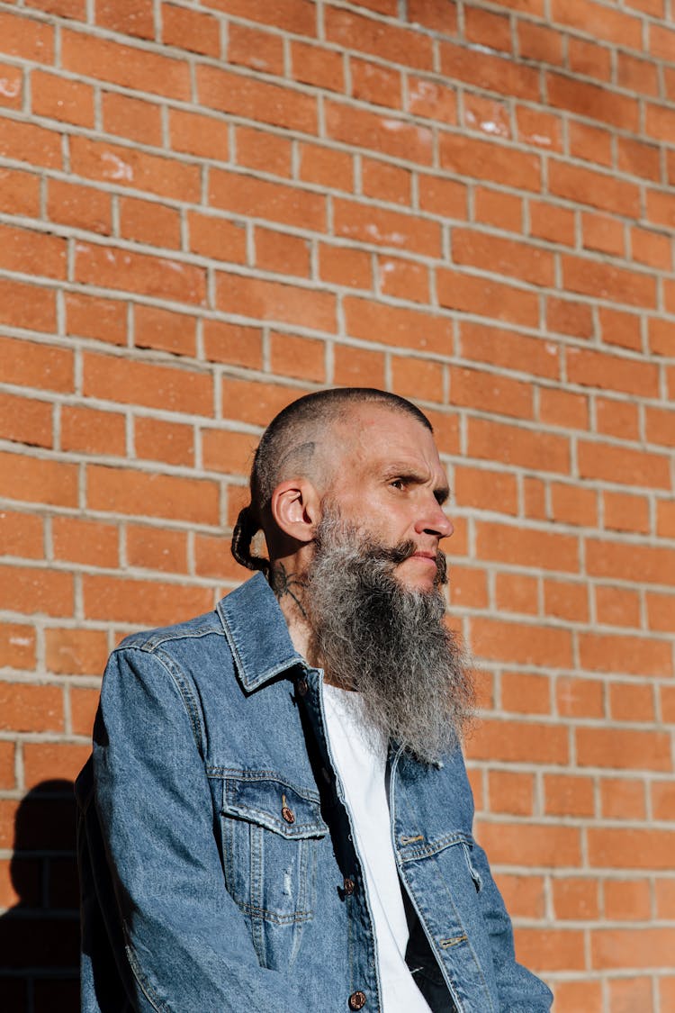 Skinny Tattooed Bearded Man Posing On Brick-Wall Background