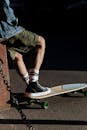 Unrecognizable Adult Male Legs in Shorts and Converse Stepping on Skateboard