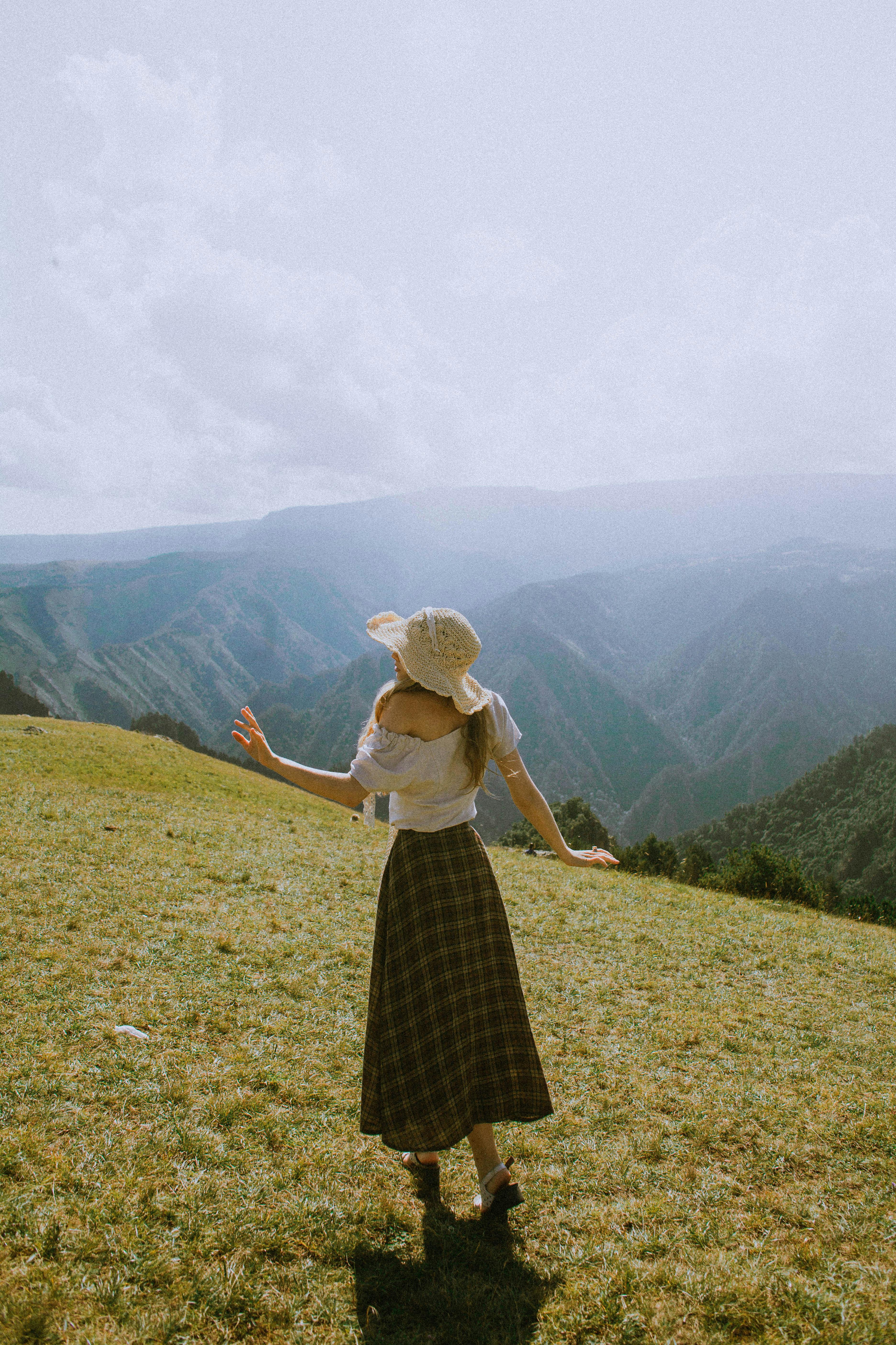 A woman in a straw hat enjoys a scenic view of mountains in Kabardino-Balkar, Russia.