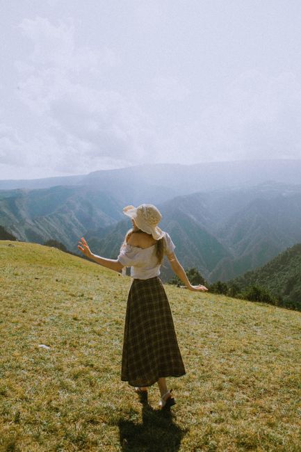 A woman in a straw hat enjoys a scenic view of mountains in Kabardino-Balkar, Russia.