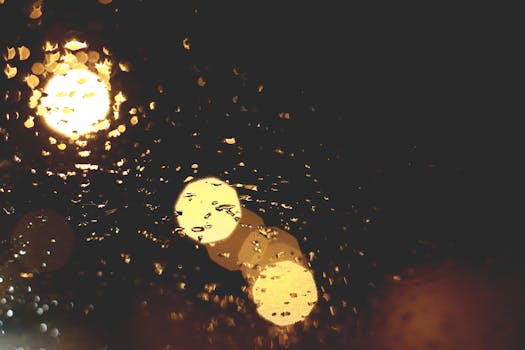 Abstract bokeh of lights through a rain-soaked window. Moody and atmospheric.