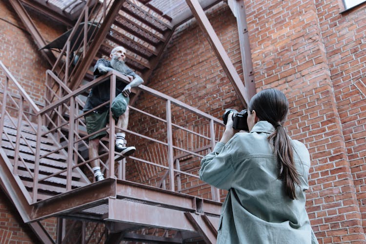 Woman Taking Picture Of A Man Standing On Stairs