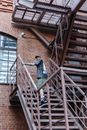 Tattooed Man in T-shirt and Shorts Going Upstairs on Outdoor Staircase