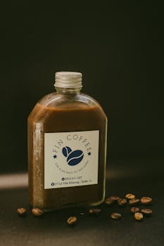 A close-up photo of a coffee bottle labeled 'Fin Coffee' with scattered beans on a dark background.