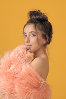 Stylish portrait of a woman wearing faux fur against a vibrant yellow backdrop.