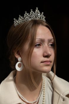 A woman adorned in a crown, earrings, and necklace, exuding elegance and poise.