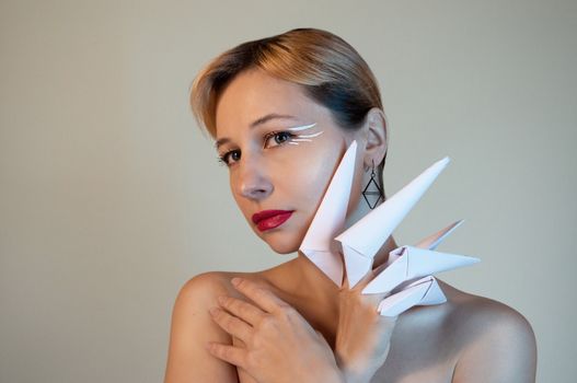 Artistic portrait of a woman with origami accessories, showcasing creativity in fashion and style.