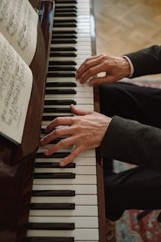 A detailed view of hands playing a piano with sheet music, showcasing musical artistry.