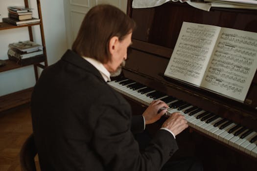 Senior man in formal attire playing piano indoors, focused on sheet music.