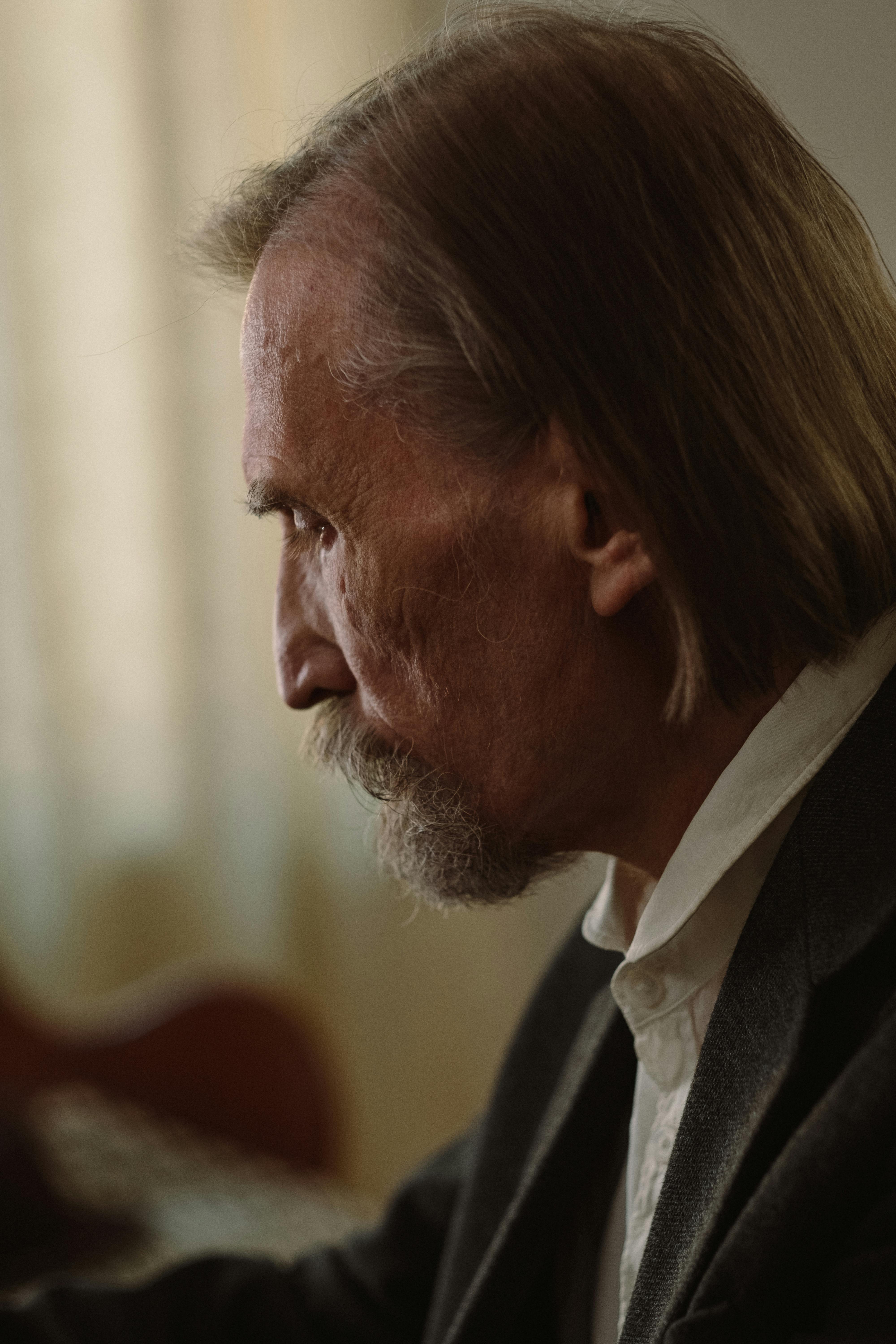 Profile of a thoughtful elderly man with a contemplative expression indoors.