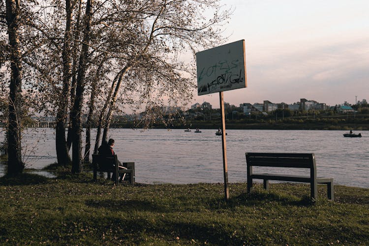 Benches And Board On Riverbank In Town