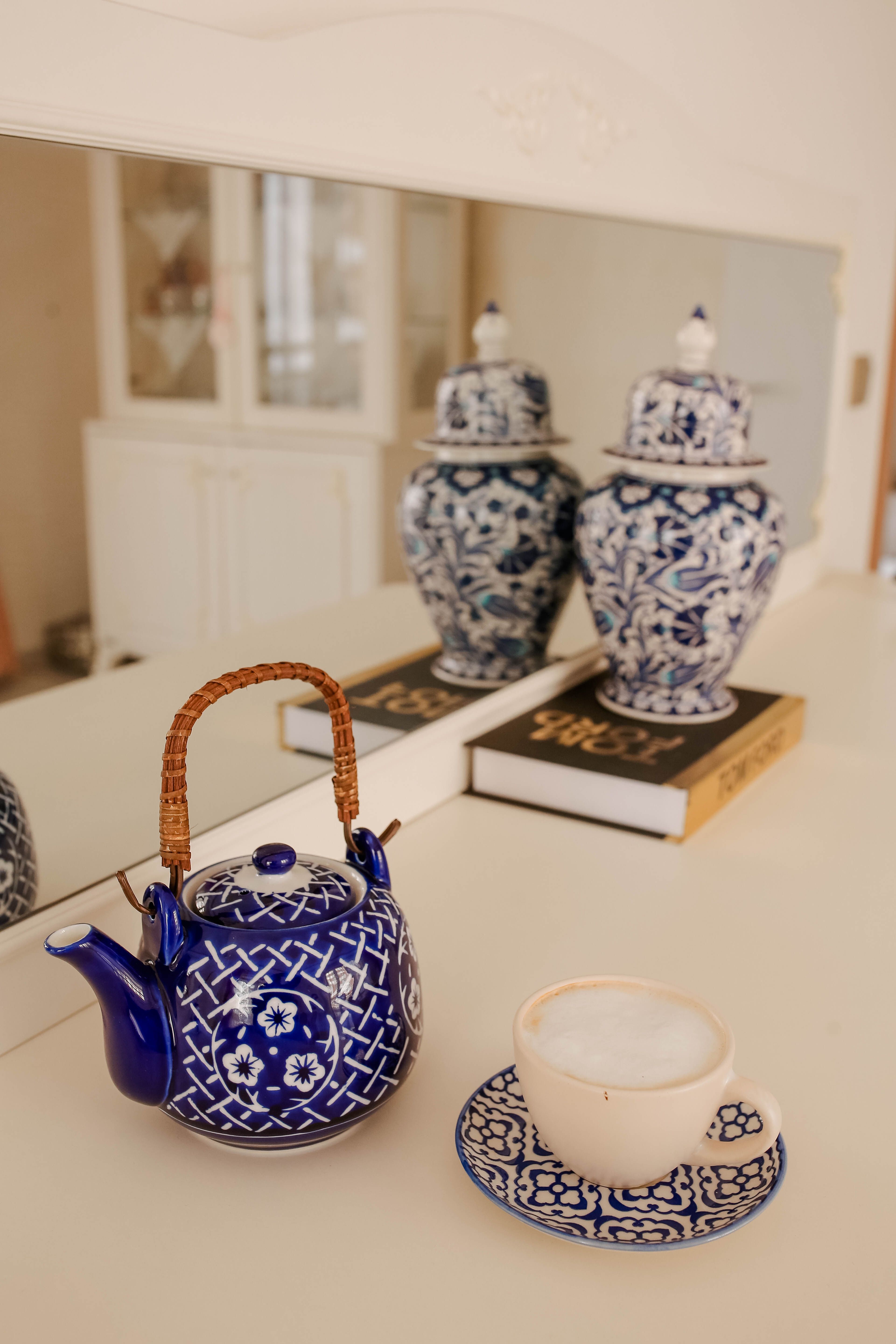 Beautiful ceramic teapot and cappuccino cup in an elegant setting with floral patterns.