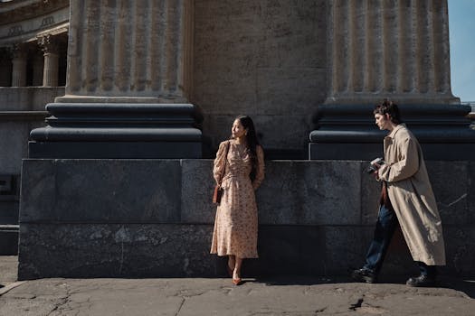 Two young adults posing in a stylish and cinematic manner next to historical columns.